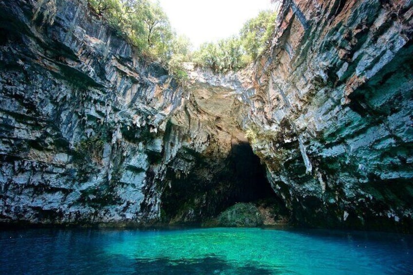 A natural cave with clear turquoise water and rocky walls. 3