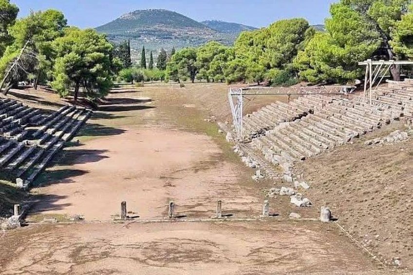 An ancient amphitheater with stone seating and a dirt stage area. 4
