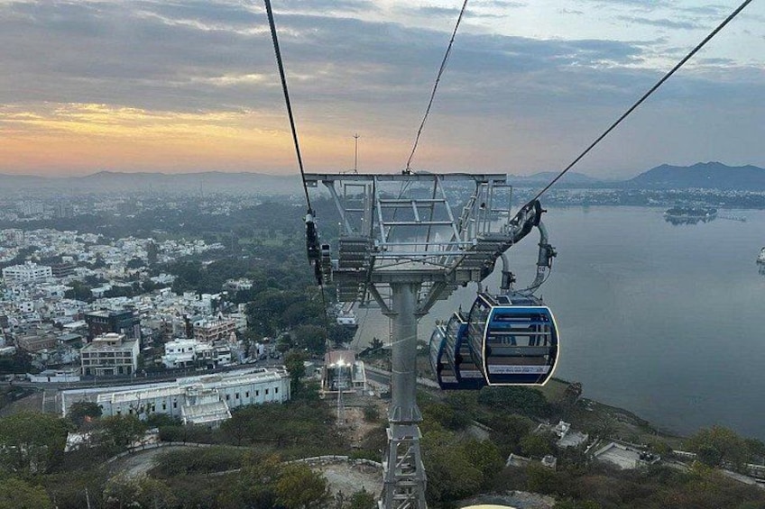 A cable car system with a cable car in motion, a body of water, and a cityscape in the background. 4