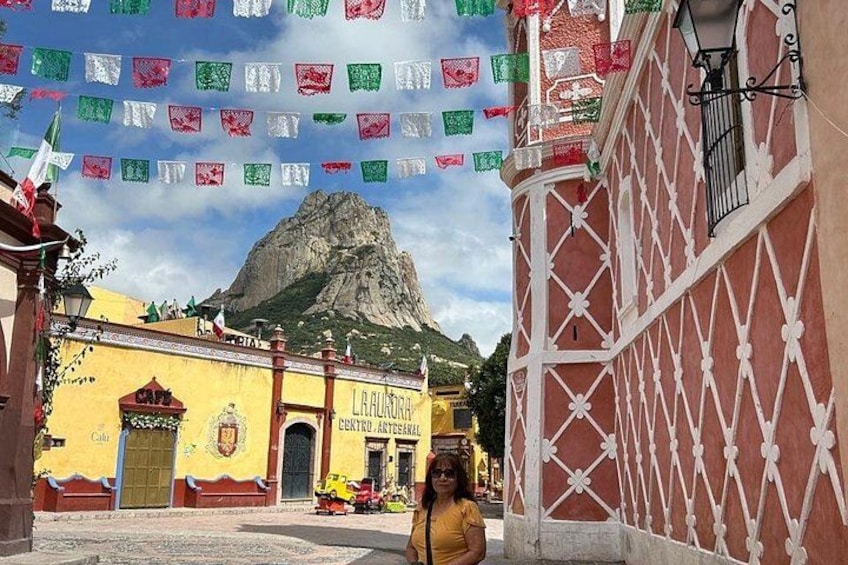 Ein Gebäude mit einem Schild, auf dem 'LA ALQUILA' steht, im Hintergrund ein Berg und bunte Fahnen, die darüber gespannt sind. 5