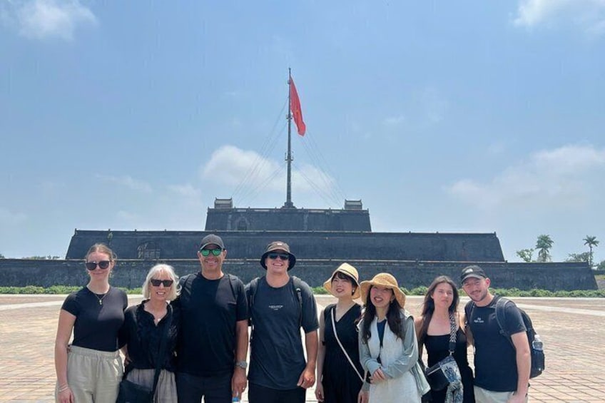 A group of people standing in front of a large historical monument with a flag. 3