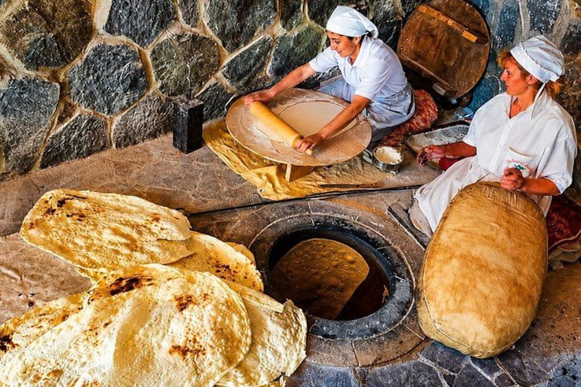 Two individuals kneading dough and a stone oven. 2