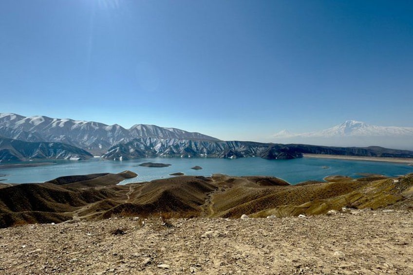 A mountainous landscape with a clear sky, a lake, and snow-capped peaks. 4