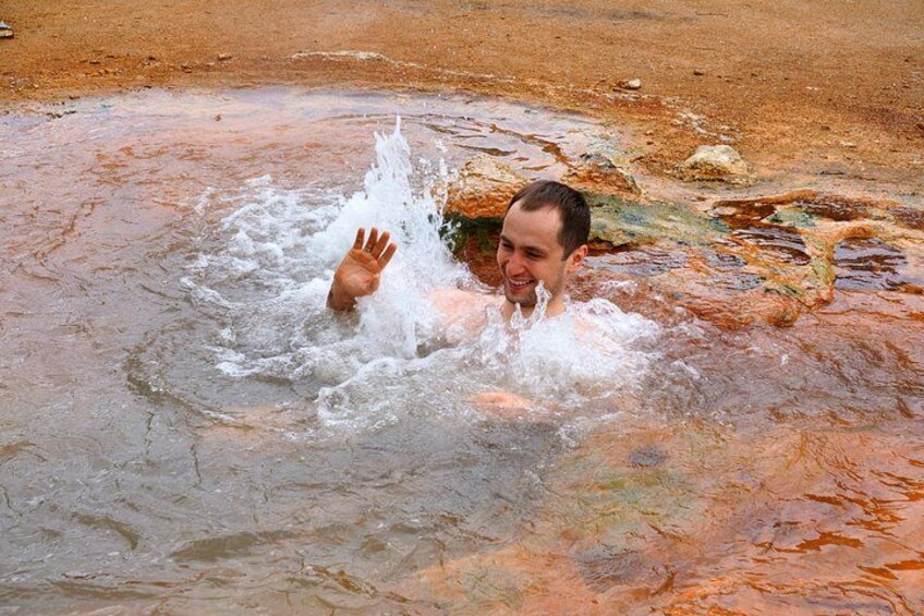 A person splashing in a body of water with reddish-brown sediment. 4