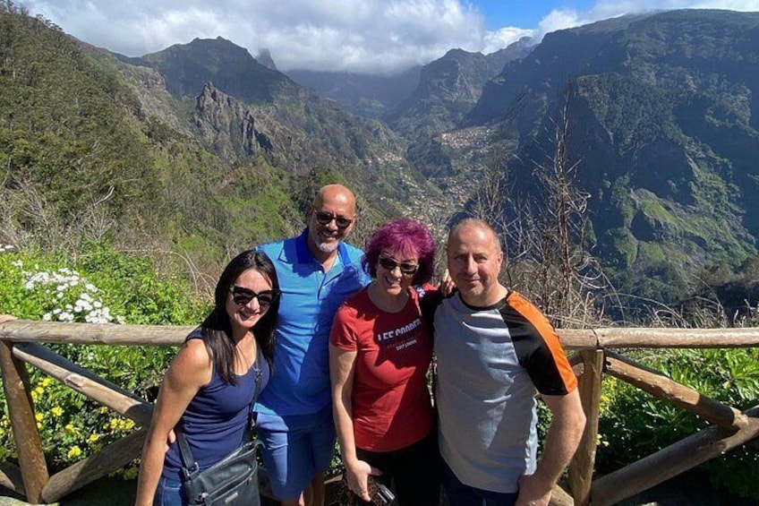 Un grupo de personas de pie sobre una plataforma de madera, con un paisaje montañoso al fondo. 1