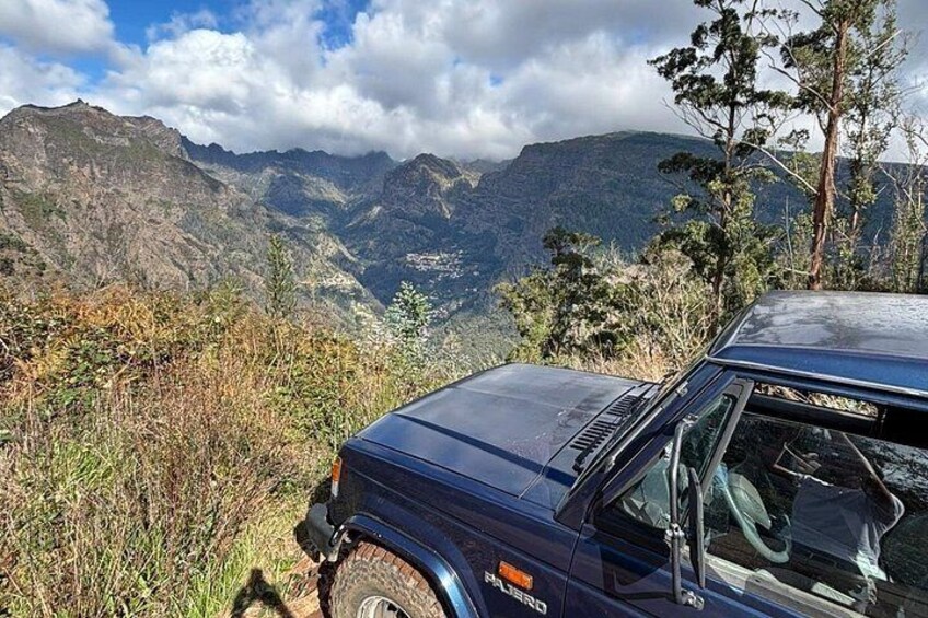 Un coche azul aparcado en una ladera con un paisaje montañoso al fondo. 5