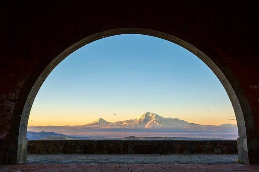 A mountain range with a prominent peak, viewed through an arched window. 3