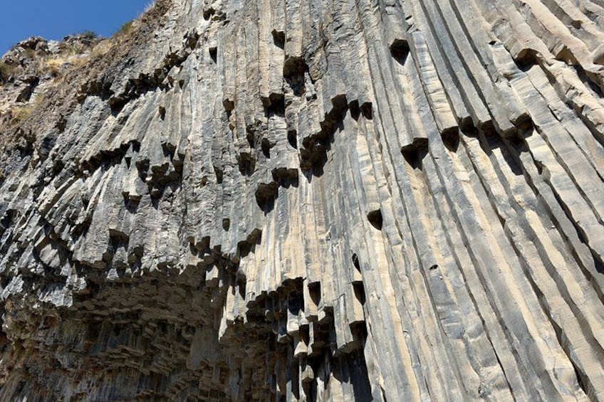 A rock face with numerous vertical striations and holes. 5