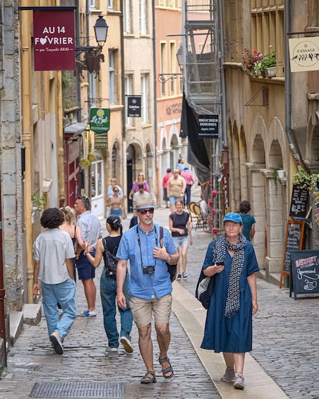 A cobblestone street with pedestrians, historic buildings, and signs for restaurants and cafes. 2