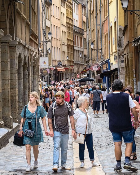 A crowded cobblestone street lined with historic buildings and shops. 1