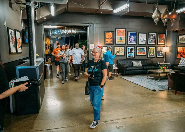 A person walking in a modern interior space with a concrete floor, a couch, a coffee table, and various framed pictures on the walls. 4