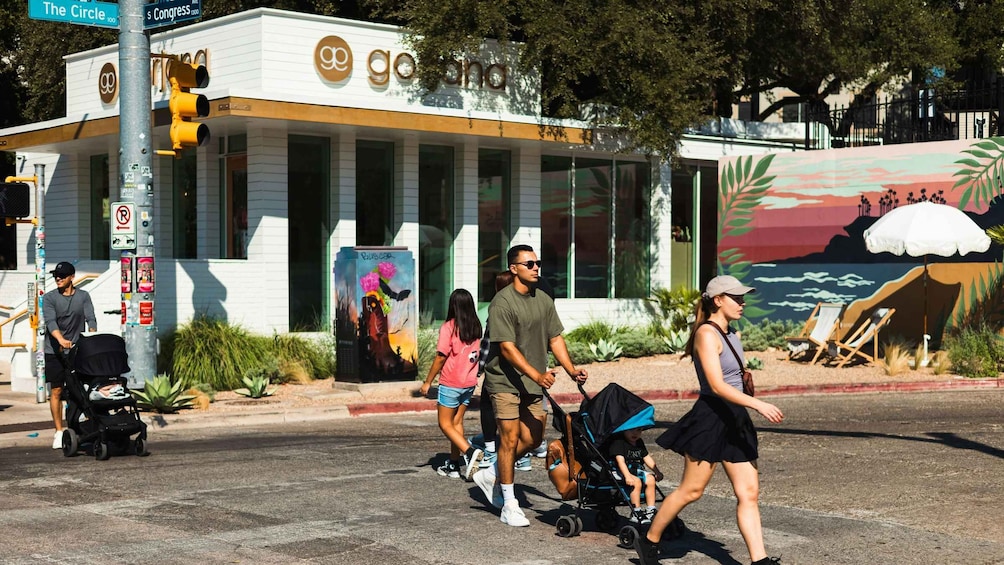 A street scene with a modern building, a mural, and pedestrians. 4