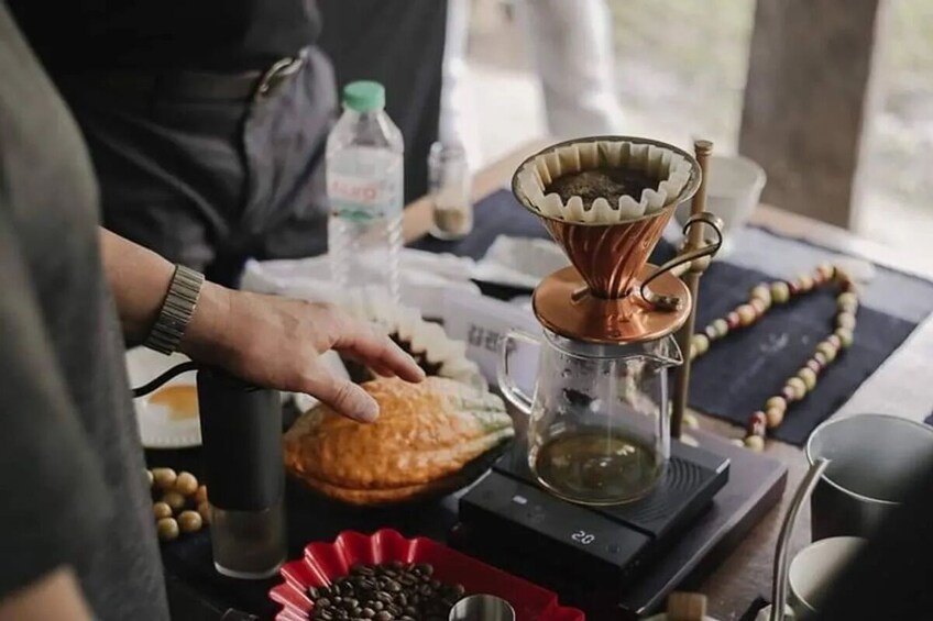 A coffee brewing setup with a drip coffee maker, a glass carafe, and a red plate with coffee beans. 2