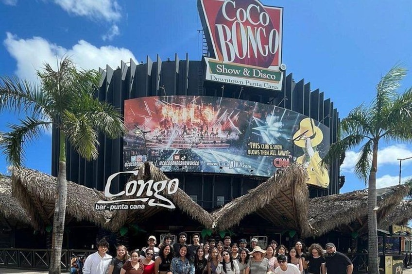 Un grupo de personas frente a un edificio con un cartel grande que anuncia un espectáculo y discoteca. 4