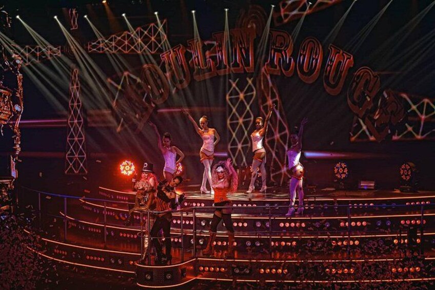Un escenario con artistas, un cartel iluminado y una multitud. 5