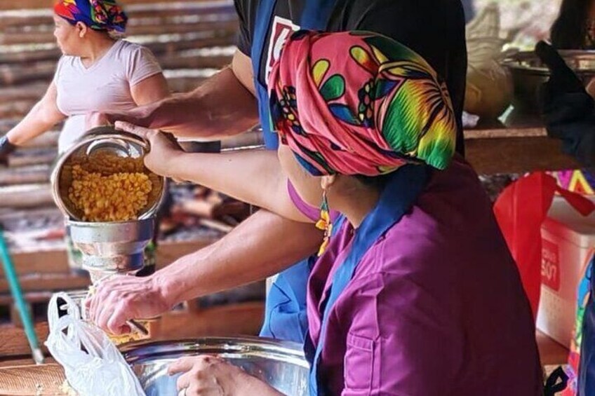 A person pouring yellow grains into a large metal bowl. 4