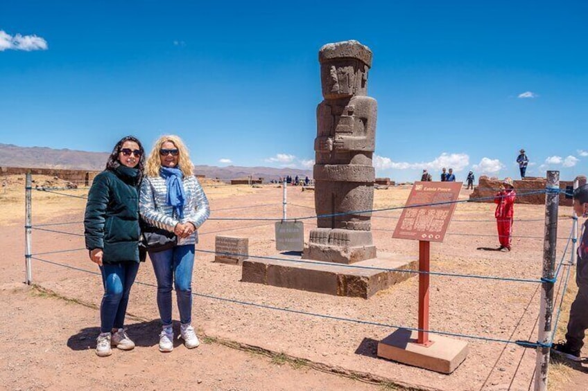 Two people standing in front of a large stone monument in a desert landscape. 3