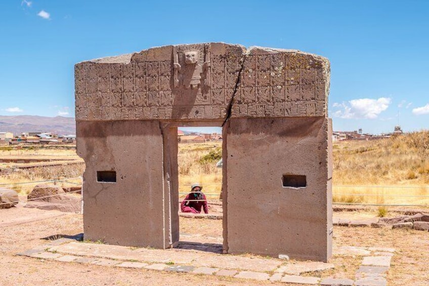 An ancient stone gateway with carvings, set in a dry landscape with sparse vegetation. 2