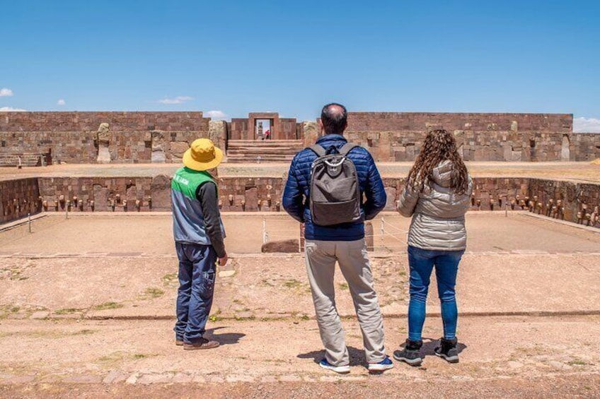 Three people standing on a dirt path looking at an ancient stone structure. 4