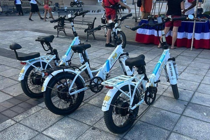 Tre elcyklar parkerade på ett kaklat underlag. 3