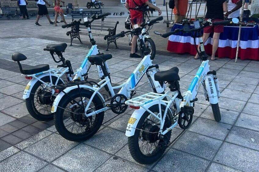 Three electric bicycles parked on a tiled surface. 4