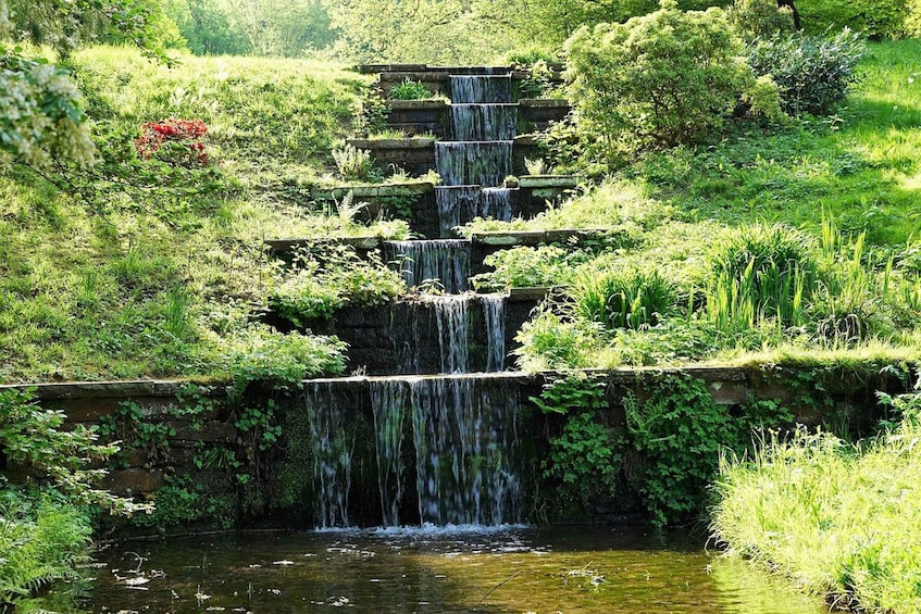 A multi-tiered waterfall cascading over a stone structure surrounded by lush greenery. 5