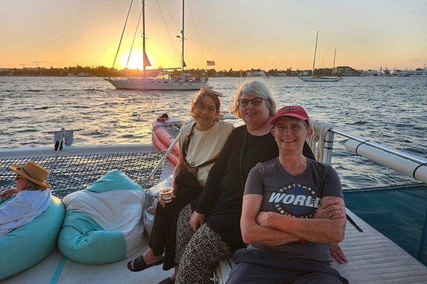 A sunset over a body of water with a sailboat and people on a dock. 2