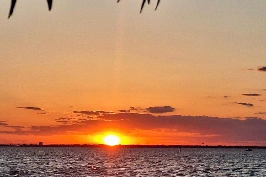 A sunset over a body of water with a silhouette of a distant structure. 5