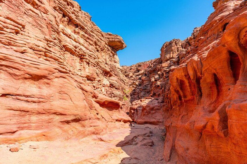 A canyon with layered red rock formations and a clear blue sky. 4
