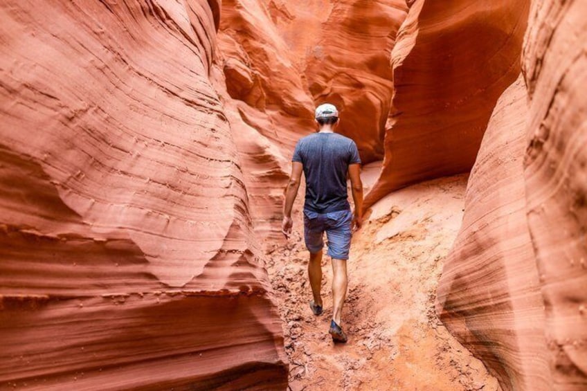 Une personne marchant dans un étroit canyon aux parois rocheuses rouges. 1