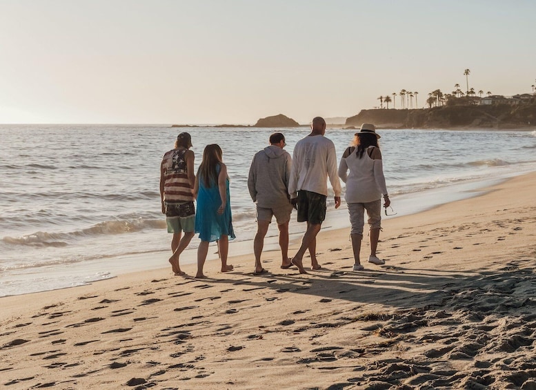 A group of people walking on a sandy beach with the ocean in the background. 2