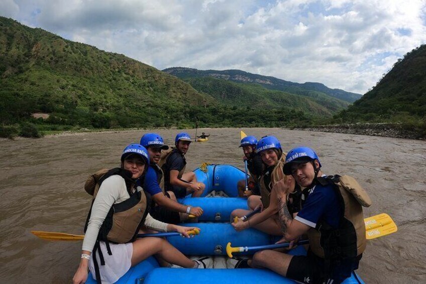 A group of people rafting on a river surrounded by green hills. 5
