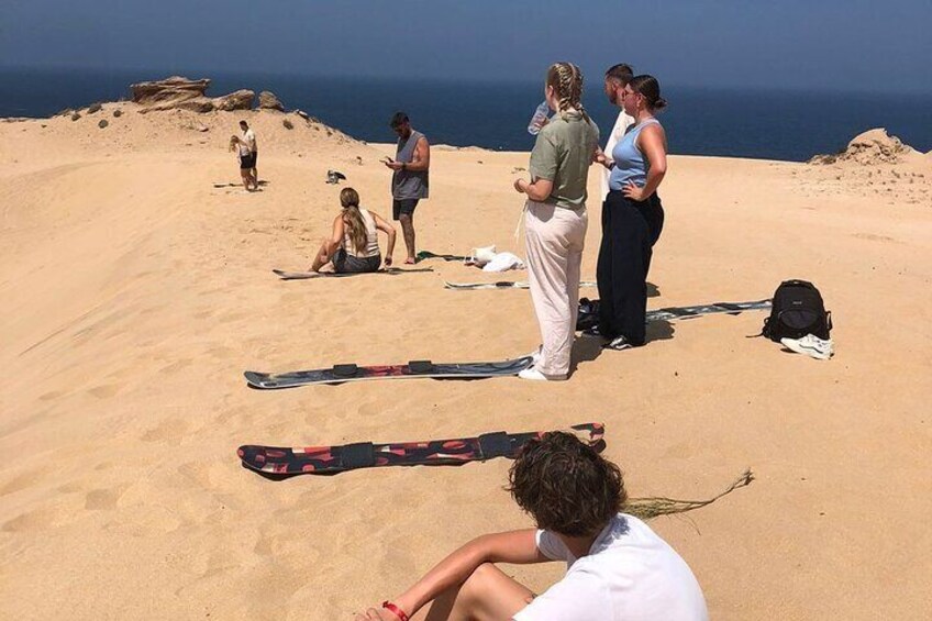 A group of people on a sandy beach with a clear sky and ocean in the background. 1