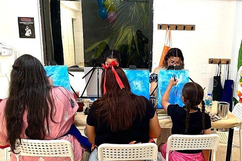 Three people painting on canvas in an outdoor setting. 4