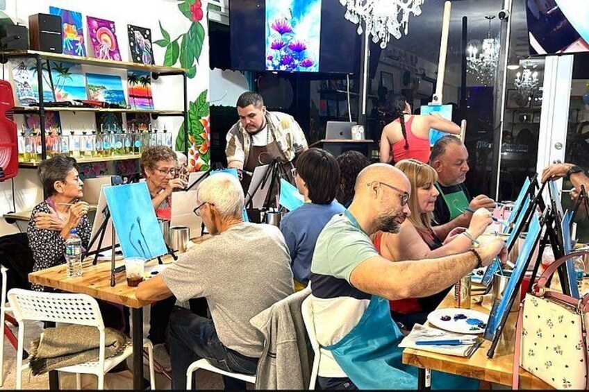 A group of people engaged in painting at a studio with easels and canvases. 3