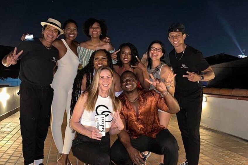 A group of people posing on a rooftop terrace at night. 2