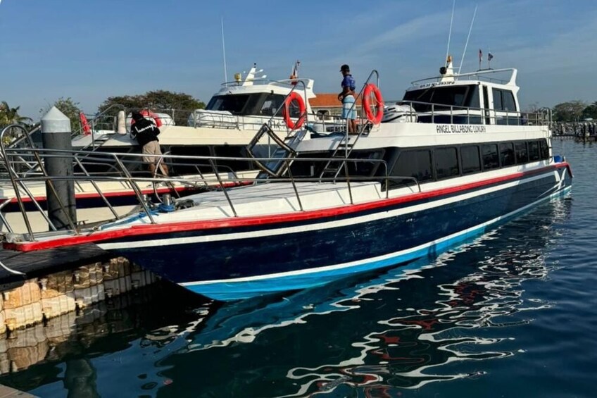 A boat docked at a pier with lifebuoys and a person on the deck. 3