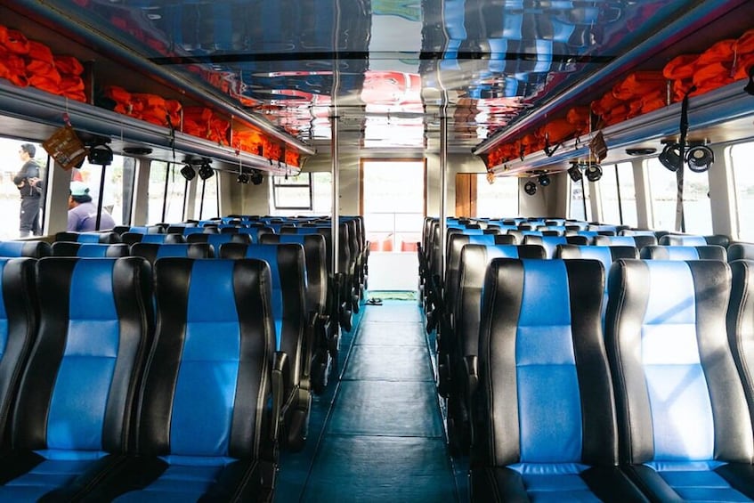 L'intérieur d'un autobus avec des sièges bleus et noirs, du matériel de sécurité rouge et un couloir dégagé. 2