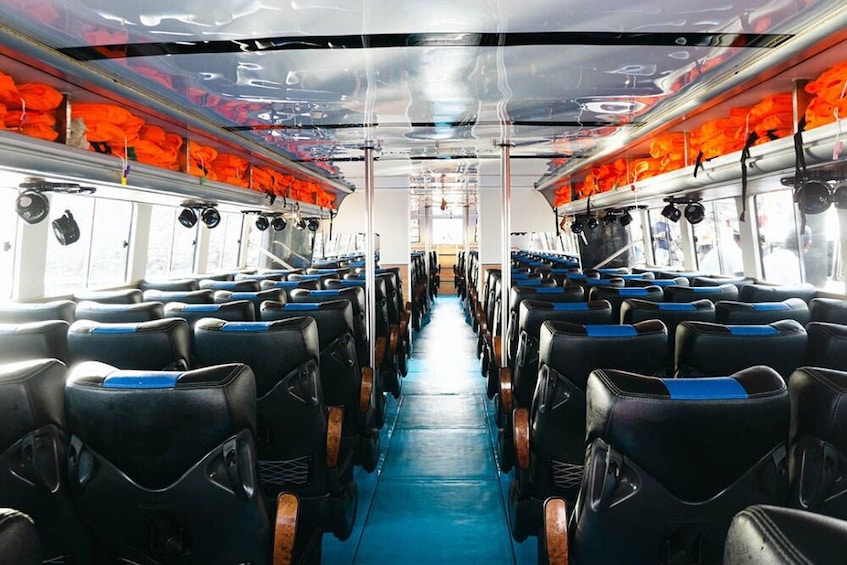 L'intérieur d'un wagon de train, avec des rangées de sièges bleus et noirs, des rideaux orange et des porte-bagages situés au-dessus des sièges. 4