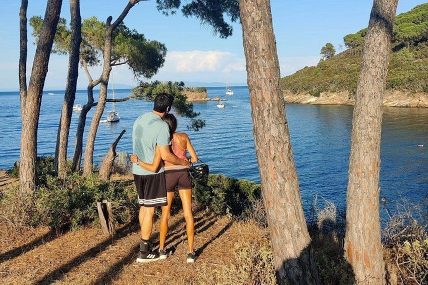 A couple standing by a coastal path with trees and a view of the sea. 3