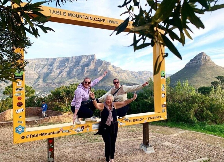 A signpost with 'Table Mountain, Cape Town' written on it, surrounded by greenery and mountains in the background. 1