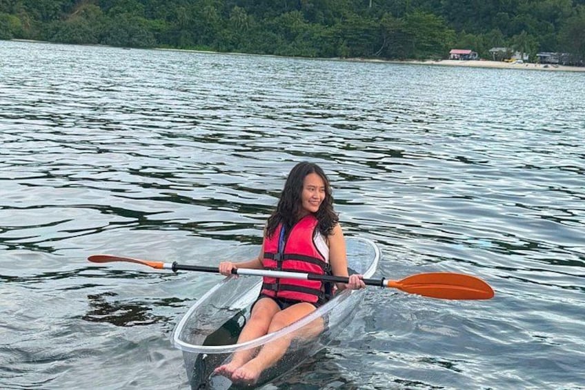 A person kayaking on a calm lake with trees and a building in the background. 4