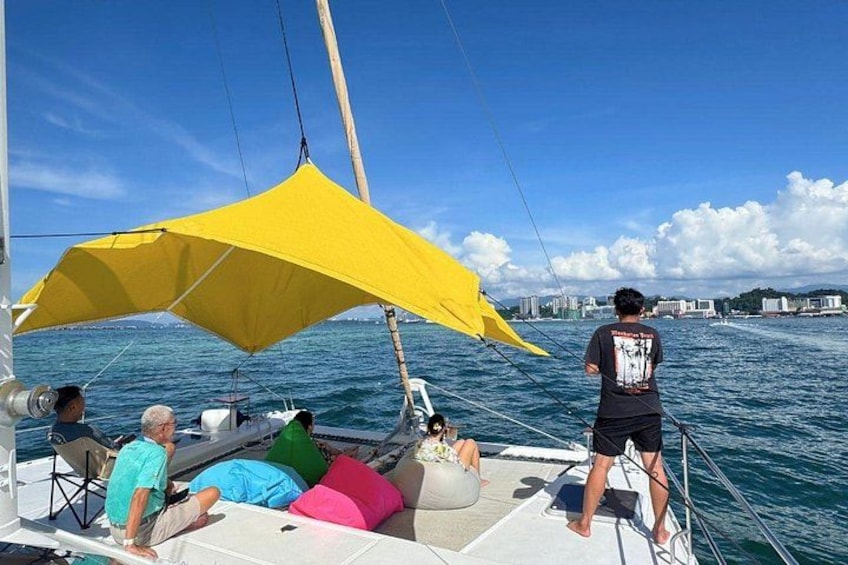 A sailboat with a yellow canopy, people on deck, and a cityscape in the background. 5