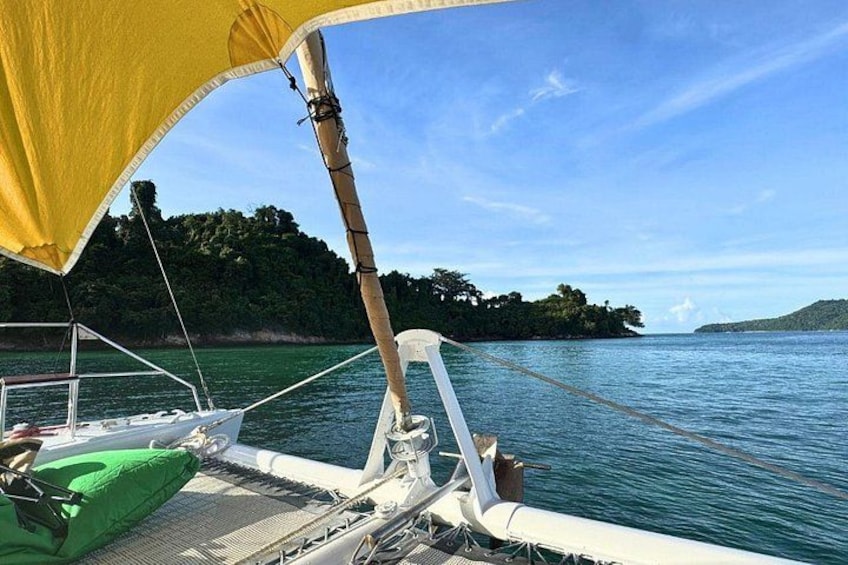 A sailboat on calm waters with a forested island in the background. 3