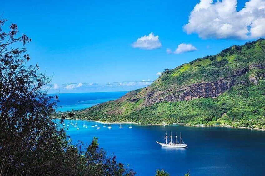 A coastal landscape with a boat on a calm sea, surrounded by lush green hills and clear blue sky. 2