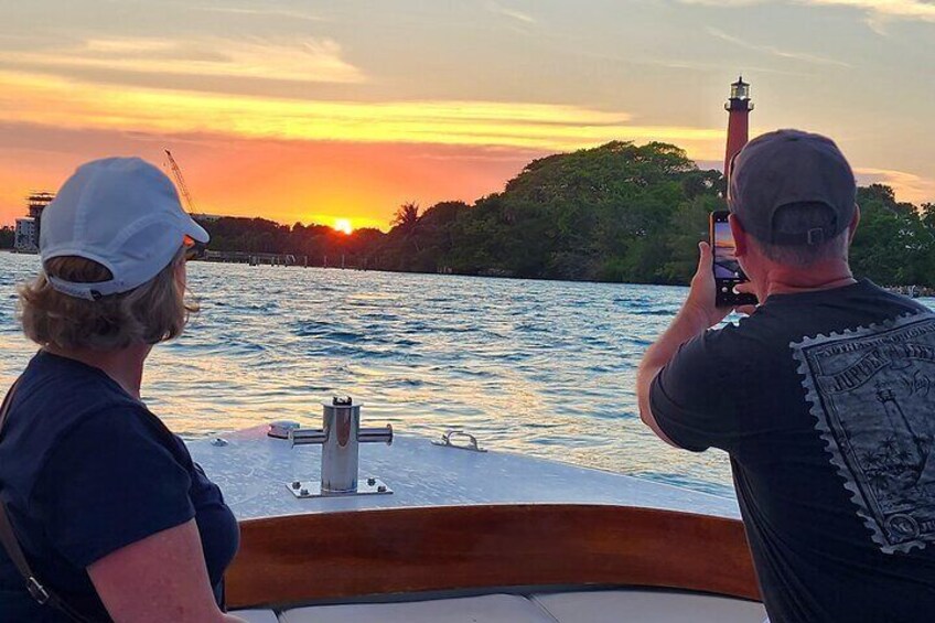 Two people on a boat taking a photo of a lighthouse at sunset. 5