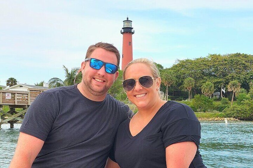 Two people on a boat with a lighthouse in the background. 2