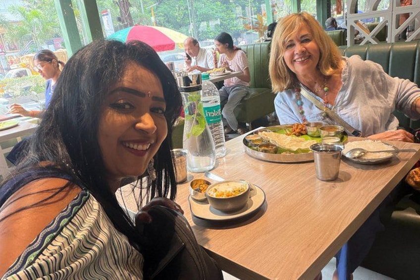 Two people dining at a restaurant with various dishes and a bottle of water on the table. 1