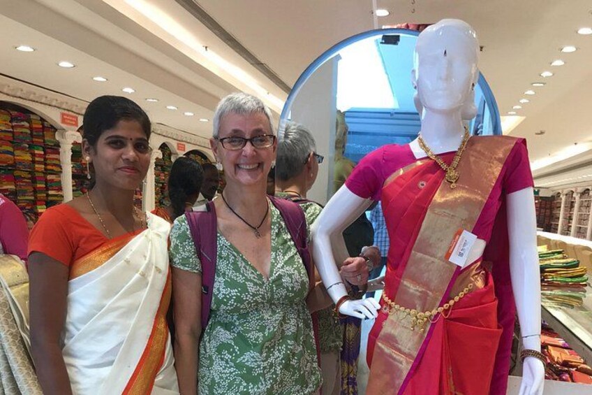 A store interior with mannequins dressed in traditional attire, a woman in a white saree, and another in a green saree. 4