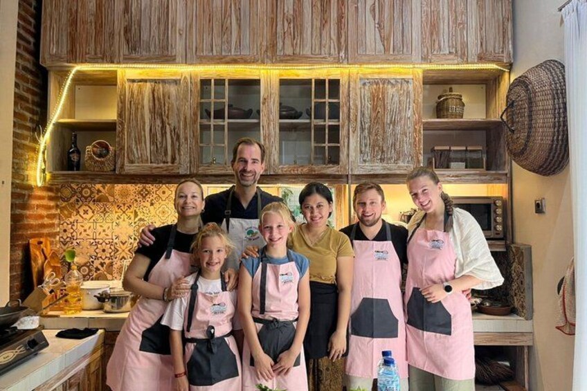 A family in a kitchen with wooden cabinets and a tiled backsplash. 1